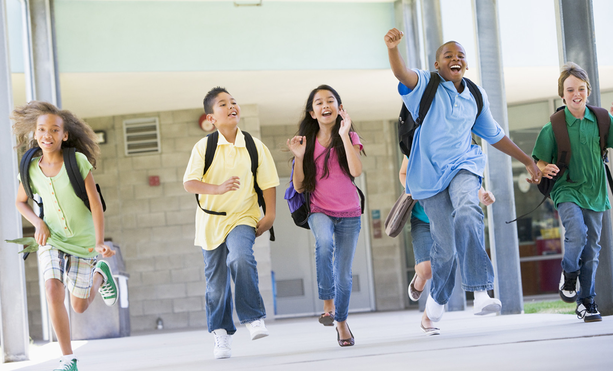 Kids with backpacks running in school.